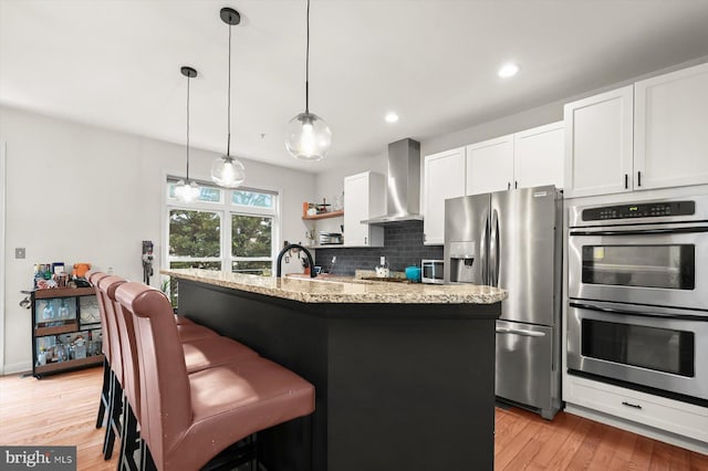 1506 Stack St, Baltimore, MD 21230 - kitchen with wall chimney range hood, appliances with stainless steel finishes, light wood-style floors, light stone counters, and recessed lighting