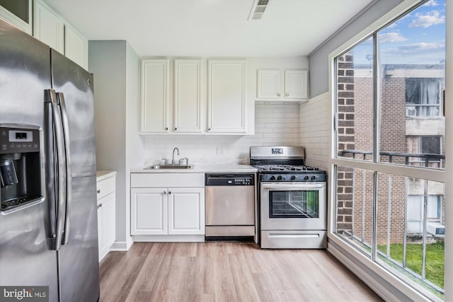 7985 Riggs Rd Unit 5, Hyattsville, MD 20783 - kitchen featuring stainless steel appliances, light countertops, light wood finished floors, decorative backsplash, and white cabinetry
