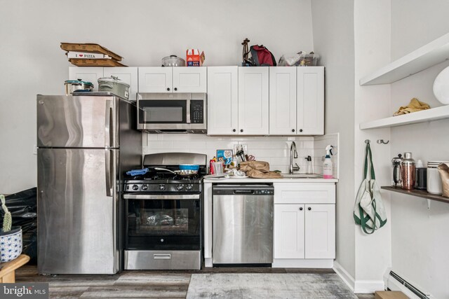 1917 Spring Garden St, Philadelphia, PA 19130 - kitchen with stainless steel appliances, a baseboard radiator, open shelves, light wood-style floors, and decorative backsplash