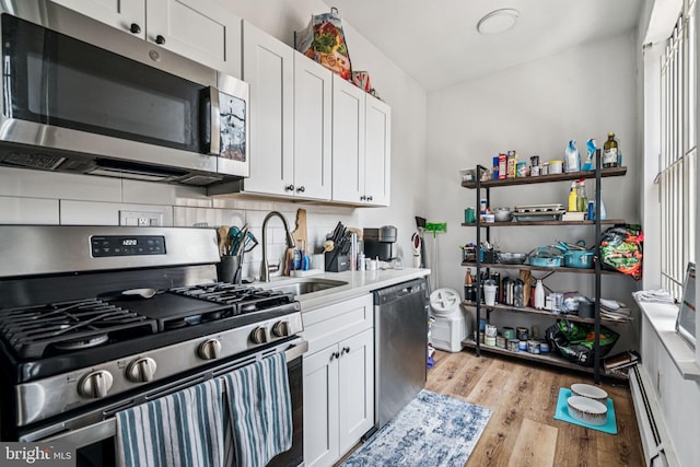 1917 Spring Garden St, Philadelphia, PA 19130 - kitchen featuring appliances with stainless steel finishes, light wood-style flooring, white cabinets, and baseboard heating