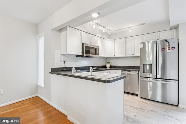 705 Westtown Cir Unit 705, West Chester, PA 19382 - kitchen with stainless steel appliances, dark countertops, a peninsula, light wood-style floors, and white cabinetry