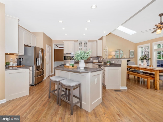 9045 Clendenin Way, Frederick, MD 21704 - kitchen featuring a peninsula, a skylight, stainless steel appliances, dark countertops, and a kitchen bar