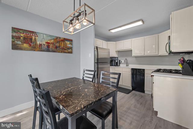 401 Cooper Landing Rd Unit 225, Cherry Hill, NJ 08002 - kitchen featuring appliances with stainless steel finishes, light wood-style floors, white cabinetry, and decorative light fixtures