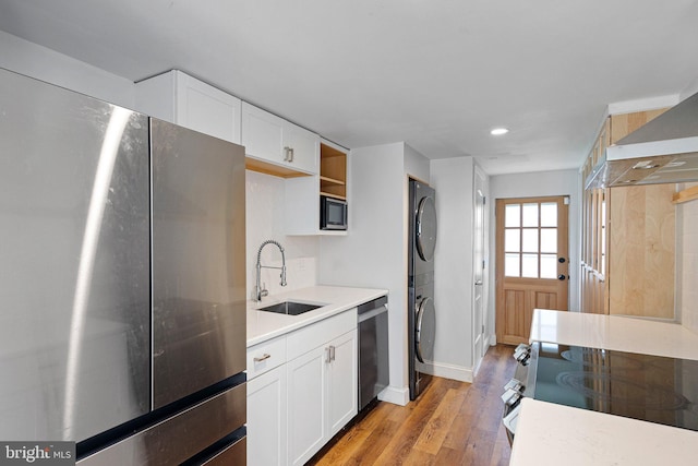 4102 N W St, Wilmington, DE 19802 - kitchen with appliances with stainless steel finishes, stacked washing machine and dryer, light wood-style flooring, light countertops, and white cabinetry