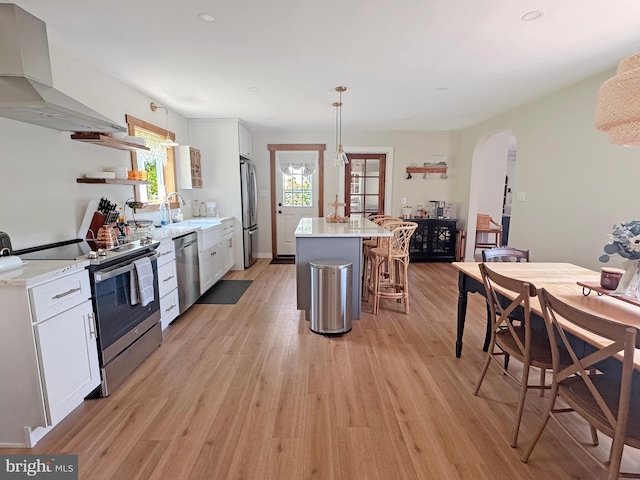 680 Myers Rd, Muncy Valley, PA 17758 - kitchen featuring stainless steel appliances, wall chimney range hood, arched walkways, a breakfast bar, and light wood-style floors