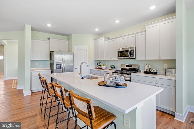 2721 Marsh Elder Dr, Cambridge, MD 21613 - kitchen featuring appliances with stainless steel finishes, a kitchen bar, a center island with sink, light wood-type flooring, and recessed lighting