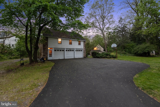 2622 Butler Pike, Plymouth Meeting, PA 19462 - property exterior at dusk featuring driveway, stone siding, a garage, and a lawn