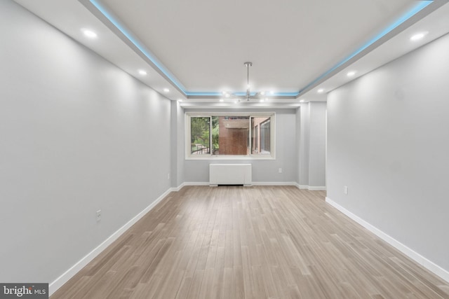 4201 Cathedral Ave NW Unit 122E, Washington, DC 20016 - unfurnished room with radiator heating unit, light wood-style flooring, a tray ceiling, and recessed lighting