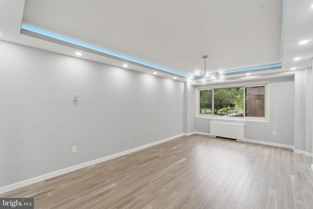 4201 Cathedral Ave NW Unit 122E, Washington, DC 20016 - empty room featuring radiator heating unit, a tray ceiling, recessed lighting, and light wood-style flooring