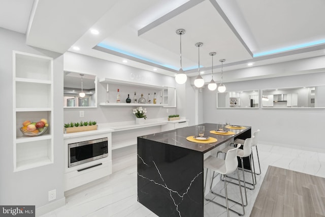 4201 Cathedral Ave NW Unit 122E, Washington, DC 20016 - kitchen featuring stainless steel microwave, modern cabinets, a raised ceiling, hanging light fixtures, and white cabinetry