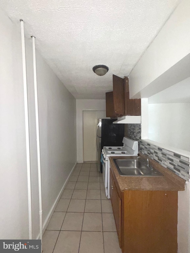 609 Bingaman St, Reading, PA 19602 - kitchen featuring white stove, under cabinet range hood, backsplash, light tile patterned floors, and a textured ceiling