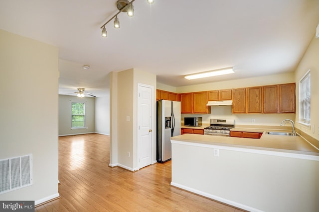6187 Les Dorson Ln, Alexandria, VA 22315 - kitchen featuring appliances with stainless steel finishes, under cabinet range hood, light countertops, a peninsula, and light wood-type flooring