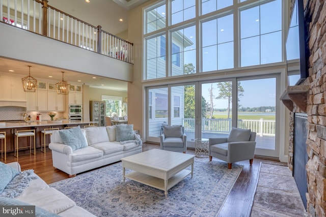 22261 Waterview Rd, Lewes, DE 19958 - living room featuring wood finished floors, a high ceiling, a fireplace, a chandelier, and a water view