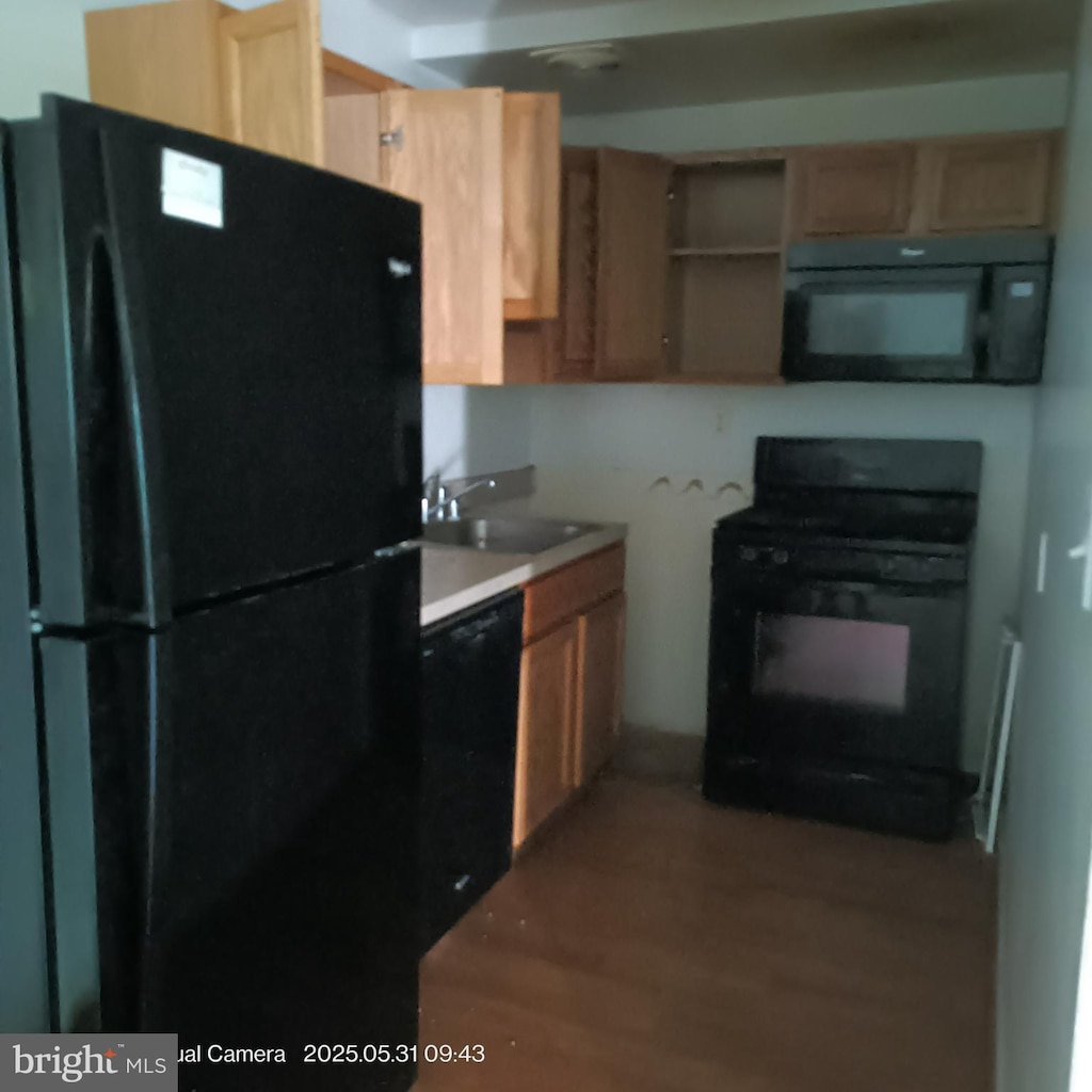 625 Chesapeake St SE Unit 206, Washington, DC 20032 - kitchen featuring black appliances, wood finished floors, light brown cabinetry, and light countertops