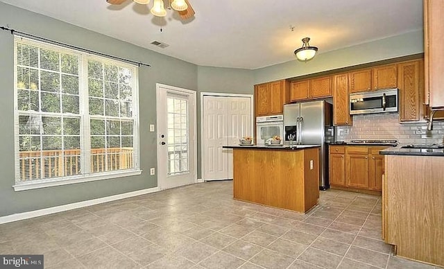 20 Harbour Heights Dr Unit 20, Annapolis, MD 21401 - kitchen with stainless steel appliances, ceiling fan, a kitchen island, dark countertops, and decorative backsplash