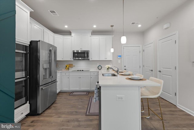 10544 Sally Ride Ln, Lanham, MD 20706 - kitchen featuring appliances with stainless steel finishes, a kitchen breakfast bar, recessed lighting, dark wood finished floors, and white cabinetry