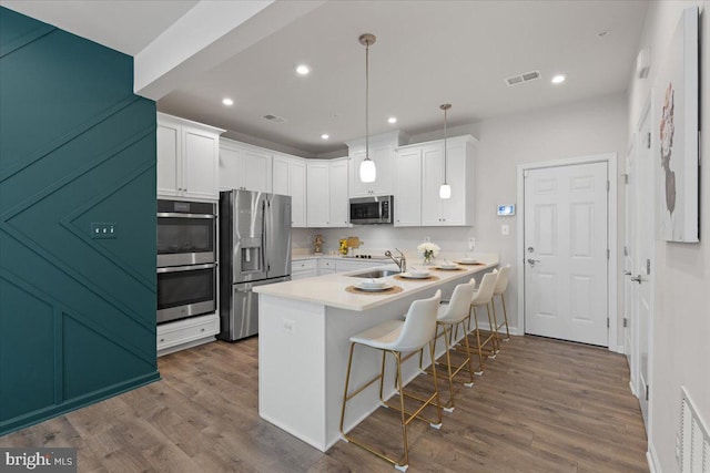 10544 Sally Ride Ln, Lanham, MD 20706 - kitchen with stainless steel appliances, a breakfast bar, white cabinetry, dark wood-style floors, and recessed lighting