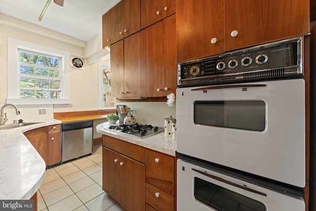 1623 Lanier Pl NW Unit 202, Washington, DC 20009 - kitchen with stainless steel appliances, light countertops, light tile patterned floors, and brown cabinetry