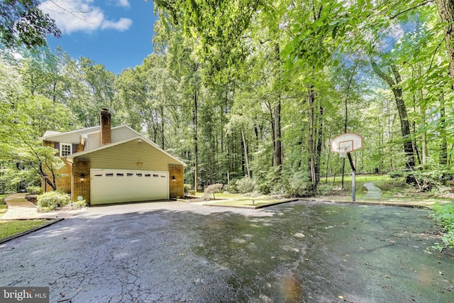 6536 Little Ox Rd, Fairfax Station, VA 22039 - view of home's exterior with a chimney, driveway, brick siding, a view of trees, and an attached garage