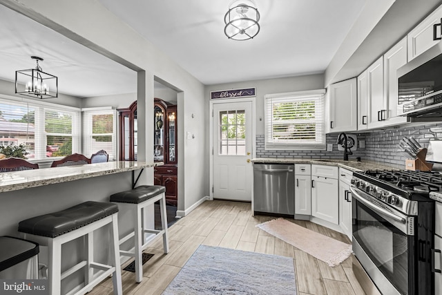 202 Cranford Rd, Cherry Hill, NJ 08003 - kitchen with appliances with stainless steel finishes, light stone countertops, white cabinets, decorative backsplash, and light wood-style floors