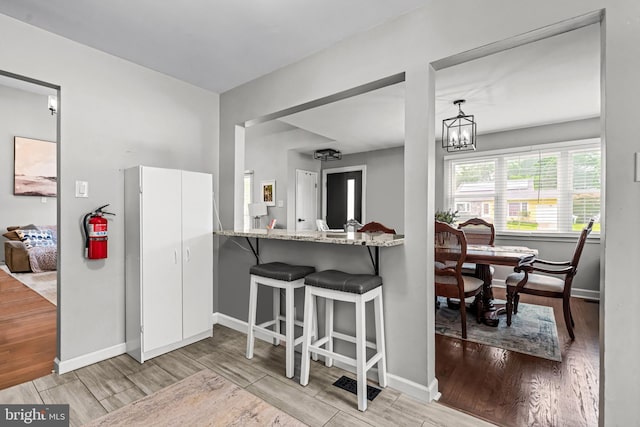 202 Cranford Rd, Cherry Hill, NJ 08003 - kitchen with wood finished floors, light stone countertops, a chandelier, a breakfast bar area, and white cabinets