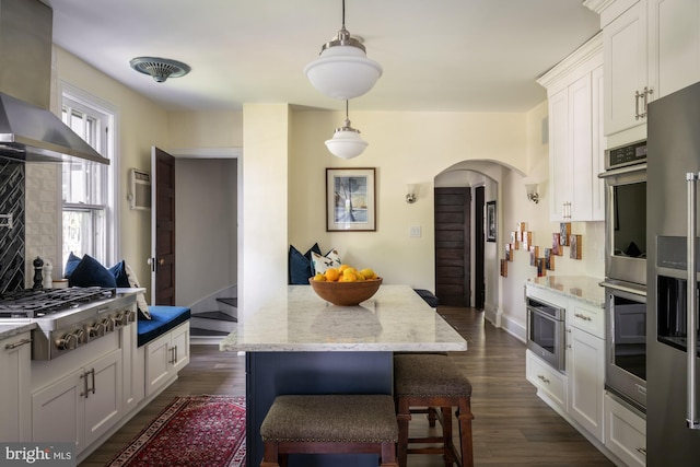 800 Main St, Riverton, NJ 08077 - kitchen with arched walkways, wall chimney range hood, stainless steel gas stovetop, white cabinets, and light stone counters