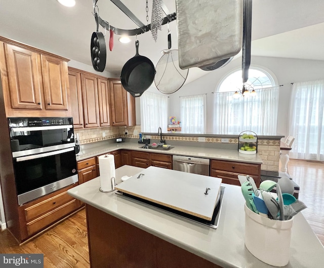 16331 Eagle Flight Cir, Woodbridge, VA 22191 - kitchen with stainless steel appliances, vaulted ceiling, light wood-type flooring, decorative backsplash, and light countertops