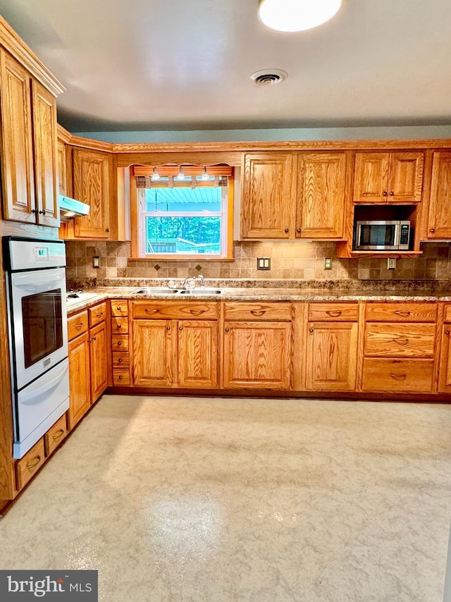 13709 Fir Tree Ln, Cresaptown, MD 21502 - kitchen featuring white appliances, a warming drawer, backsplash, under cabinet range hood, and brown cabinets