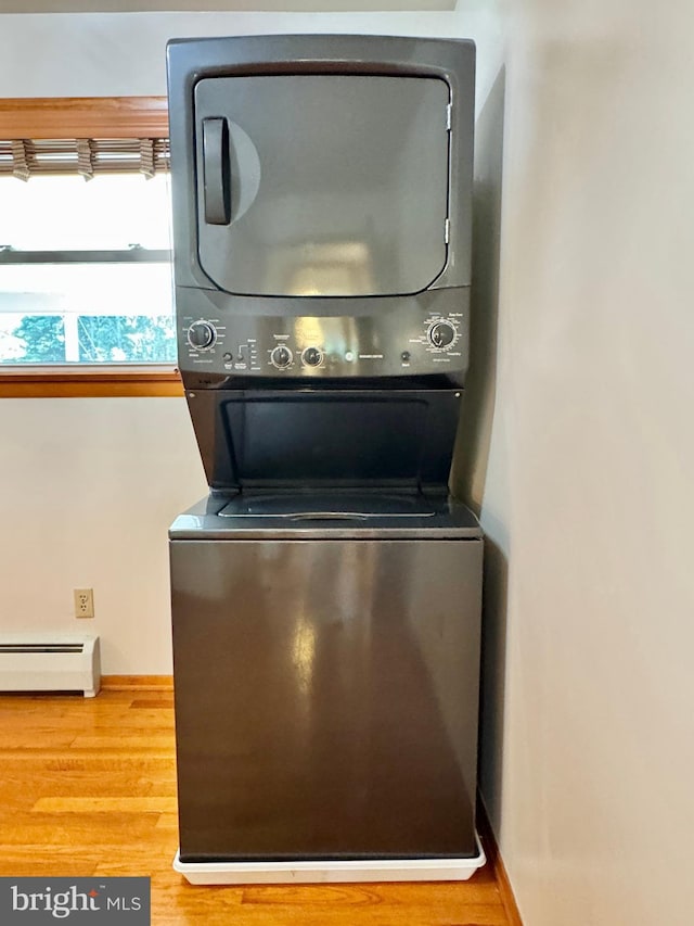 13709 Fir Tree Ln, Cresaptown, MD 21502 - laundry room featuring a baseboard radiator, stacked washing machine and dryer, and wood finished floors