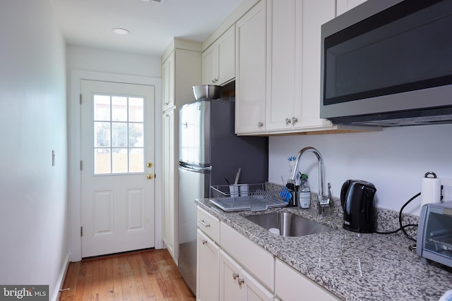 3238 P St NW, Washington, DC 20007 - kitchen featuring stainless steel appliances, white cabinets, light wood finished floors, light stone countertops, and recessed lighting