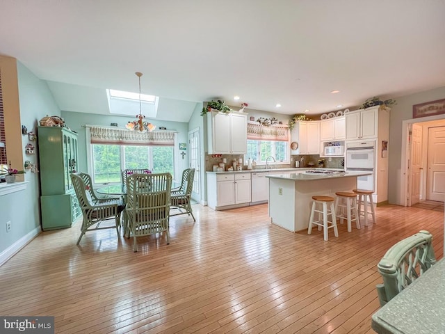 19 Pheasant Run Rd, New Hope, PA 18938 - kitchen with white appliances, white cabinets, decorative backsplash, light wood finished floors, and a kitchen breakfast bar