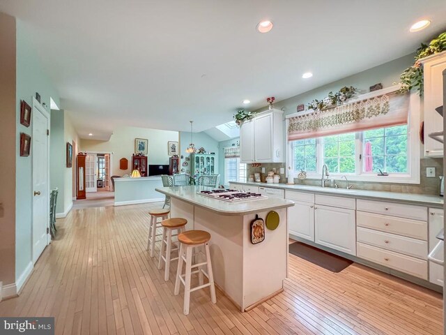 19 Pheasant Run Rd, New Hope, PA 18938 - kitchen with light wood-style flooring, white cabinetry, a kitchen island, light countertops, and a kitchen bar