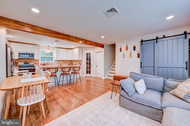 215 Murray Dr, Doylestown, PA 18901 - living room featuring a barn door, light wood-style floors, recessed lighting, stairs, and beam ceiling