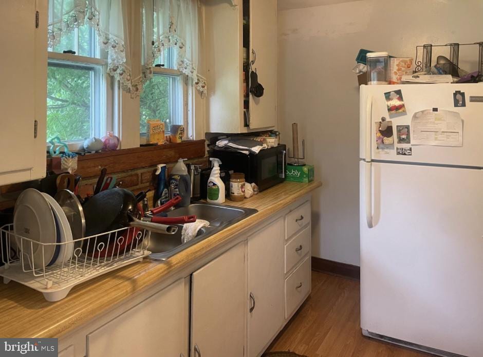 531 Winifred Rd, Cumberland, MD 21502 - kitchen featuring freestanding refrigerator, light countertops, white cabinetry, black microwave, and light wood-style flooring