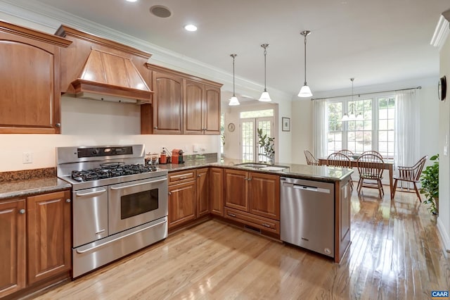 455 Foxdale Ln, Charlottesville, VA 22903 - kitchen with stainless steel appliances, premium range hood, light wood-style flooring, brown cabinetry, and pendant lighting