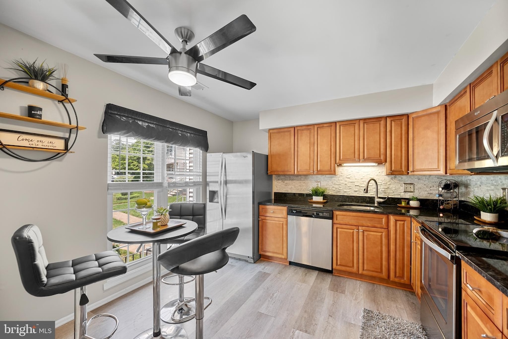 2870 Burgundy Pl, Woodbridge, VA 22192 - kitchen featuring stainless steel appliances, light wood finished floors, decorative backsplash, a ceiling fan, and brown cabinets