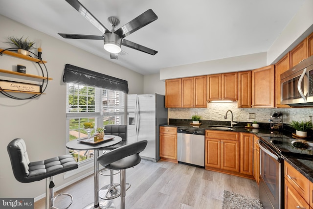 2870 Burgundy Pl, Woodbridge, VA 22192 - kitchen featuring stainless steel appliances, light wood finished floors, decorative backsplash, a ceiling fan, and brown cabinets