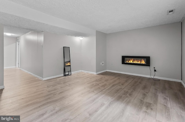 9355 Pan Ridge Rd Unit 9355, Parkville, MD 21234 - unfurnished living room featuring a textured ceiling, wood finished floors, and a glass covered fireplace