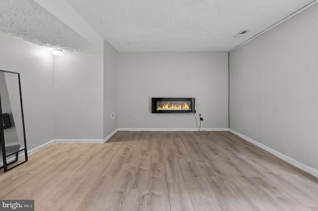 9355 Pan Ridge Rd Unit 9355, Parkville, MD 21234 - unfurnished living room featuring wood finished floors, a glass covered fireplace, and a textured ceiling