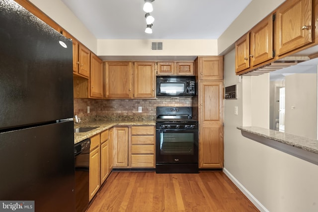 11021 Folksie Ct Unit 201, Manassas, VA 20109 - kitchen with black appliances, tasteful backsplash, light wood-style floors, and light stone countertops