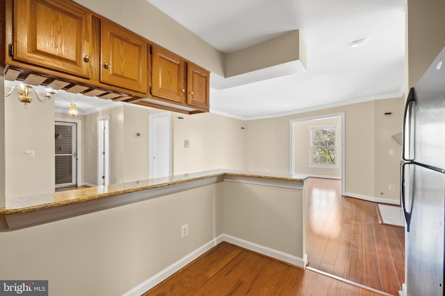 11021 Folksie Ct Unit 201, Manassas, VA 20109 - kitchen with freestanding refrigerator, light wood-type flooring, brown cabinetry, light stone countertops, and ornamental molding