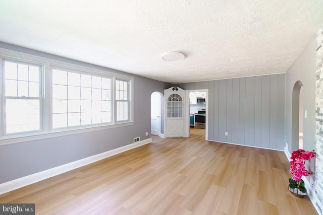 6 Carroll Rd, Catonsville, MD 21228 - unfurnished living room featuring arched walkways, light wood-style flooring, and a textured ceiling