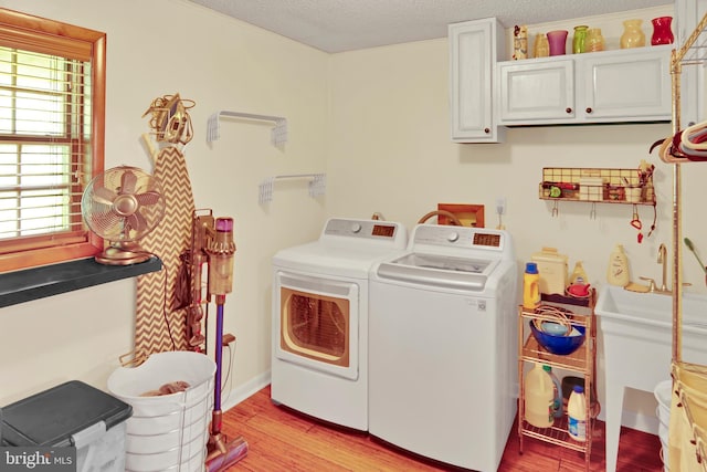 20412 Holt Cir, Hagerstown, MD 21742 - laundry room with washing machine and clothes dryer, cabinet space, light wood-type flooring, and a textured ceiling