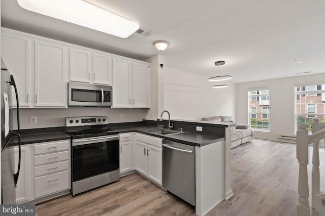19278 Harlow Sq, Leesburg, VA 20176 - kitchen featuring stainless steel appliances, dark countertops, open floor plan, a peninsula, and white cabinetry