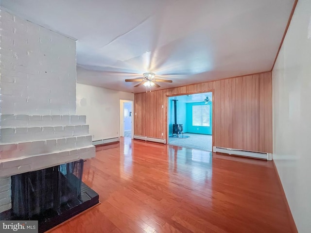 237 Lakeside Dr Unit N, Levittown, PA 19054 - unfurnished living room featuring a baseboard radiator, wood finished floors, ceiling fan, a fireplace, and wood walls