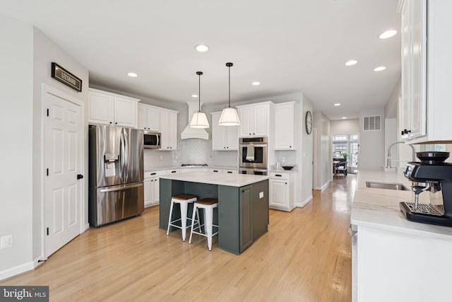 18416 Mill Run Ct, Leesburg, VA 20176 - kitchen with appliances with stainless steel finishes, light wood finished floors, white cabinets, a kitchen island, and recessed lighting