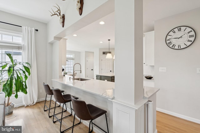 18416 Mill Run Ct, Leesburg, VA 20176 - kitchen with light wood-style flooring, light stone countertops, a kitchen bar, white cabinets, and recessed lighting