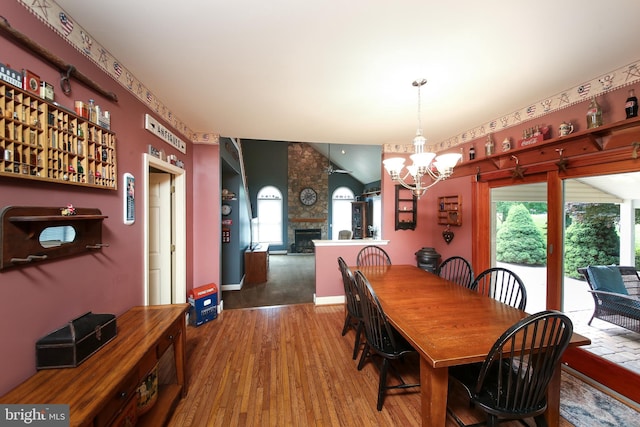 2553 Stone Hill Rd, Harleysville, PA 19438 - dining area with wood finished floors, a stone fireplace, a chandelier, and vaulted ceiling