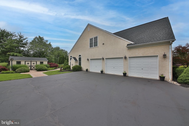 2553 Stone Hill Rd, Harleysville, PA 19438 - view of home's exterior with driveway, stucco siding, a shingled roof, a garage, and an outbuilding