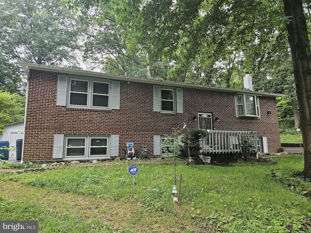 18301 Nob Hill Dr, Triangle, VA 22172 - bi-level home featuring a chimney, brick siding, a front yard, and a wooden deck